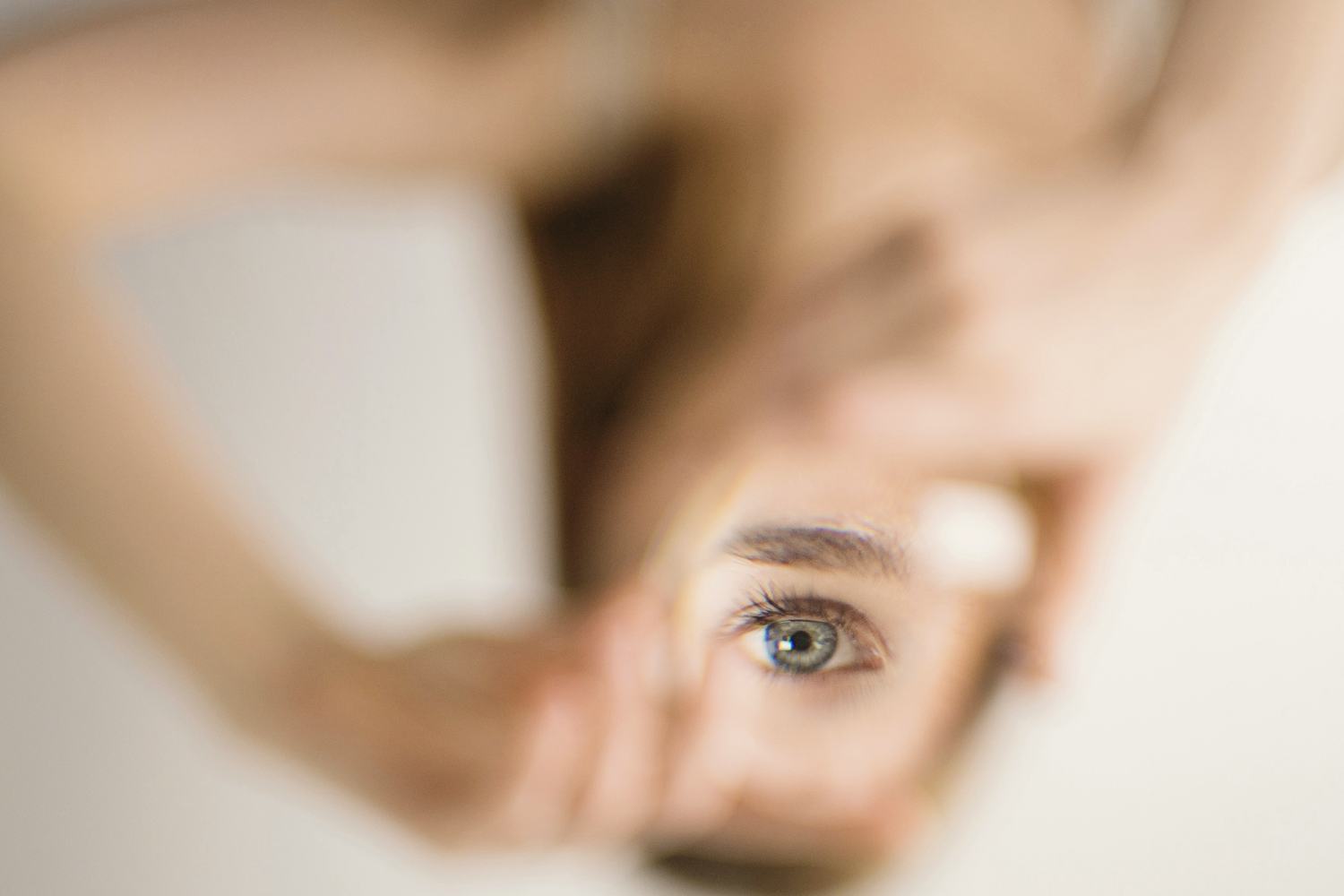 Un regard aperçu entre deux mains.