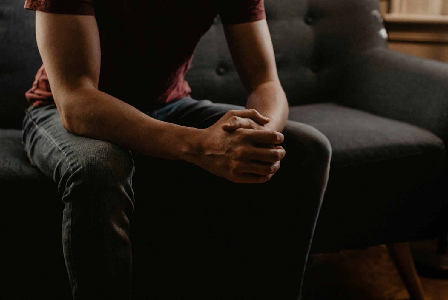 Une personne assise, les mains jointes, pendant une consultation.